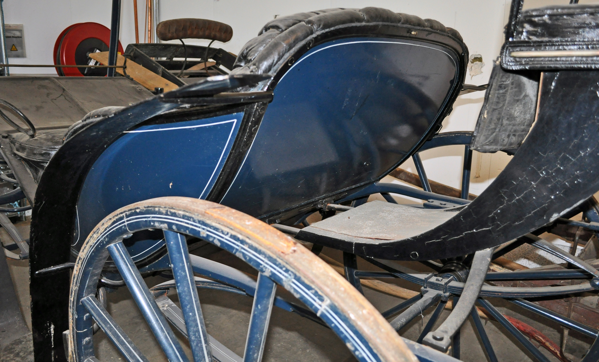 Fra protokollen: Trille, for en hest. Plass til 4 personer + kusk bak. Skinntrekk sete. Vogna er utstyrt med brems og har jerngjorder på hjula. Blålakkert med kvite render. Phaeton-trille.