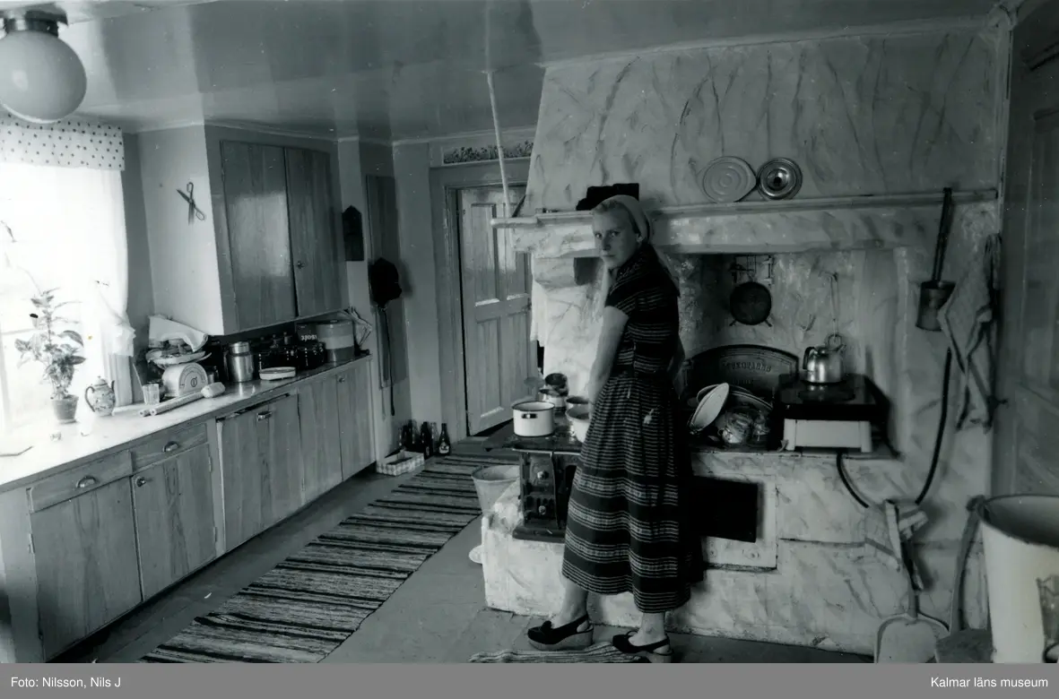Interiör hos fru Ann Mari Johnsson. Fru Johnsson vid spisen.