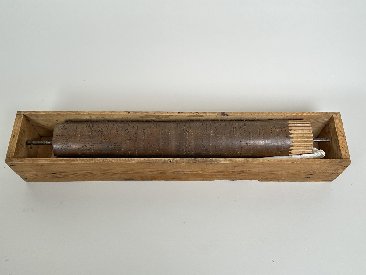 A) Pianoharpa, i form av ett skrivbord av mazarin-typ. Av mörkt betsat och polerat trä. Skrivbordet kraftigt angripet av trägnagare. Svarvade ben och hög sarg, med två utdragbara lådor och tre blindlådor - alla med mässingsbeslag. Bordsskivan uppfällbar och ställbar med metallhake, varunder spelverket med strängar och piggförsedd vals gömmer sig. 
B) och C), två valsar med olika melodier på. Cylinderformade, av trä, med mittaxel och piggar av metall. Valsen snurras med en vev, som lämnat ett svängt märke på möbelns front. 
D), vev av tunn metallarm med ett S-formad avslut i 45 graders vinkel från armen samt svarvad, balusterformat handtag av trä.
E) och F), stämnycklar av metall med fyrkantiga hål, samt enkla handtag av trä. 
G), sprint av metall för att säkra valsen på plats. Tunn, med ögla till avslut.
H), förvaringslåda för melodivals. Av trä, med inbyggd vagga för att hålla valsens mittaxel.