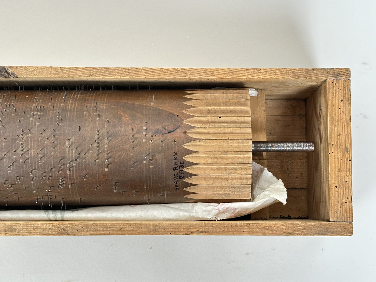 A) Pianoharpa, i form av ett skrivbord av mazarin-typ. Av mörkt betsat och polerat trä. Skrivbordet kraftigt angripet av trägnagare. Svarvade ben och hög sarg, med två utdragbara lådor och tre blindlådor - alla med mässingsbeslag. Bordsskivan uppfällbar och ställbar med metallhake, varunder spelverket med strängar och piggförsedd vals gömmer sig. 
B) och C), två valsar med olika melodier på. Cylinderformade, av trä, med mittaxel och piggar av metall. Valsen snurras med en vev, som lämnat ett svängt märke på möbelns front. 
D), vev av tunn metallarm med ett S-formad avslut i 45 graders vinkel från armen samt svarvad, balusterformat handtag av trä.
E) och F), stämnycklar av metall med fyrkantiga hål, samt enkla handtag av trä. 
G), sprint av metall för att säkra valsen på plats. Tunn, med ögla till avslut.
H), förvaringslåda för melodivals. Av trä, med inbyggd vagga för att hålla valsens mittaxel.