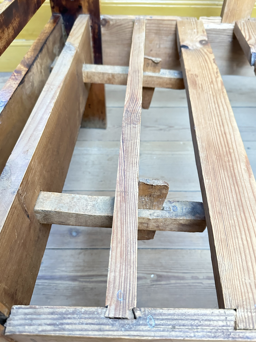 Hörnsoffa i polerad björk med stoppad sits. Genombrutna gavlar med två tvärslåar och spjälor däremellan. Intarsia på gavlarnas kortsidor i form av solfjäderlik halvcirkel samt små rektangulära tegelformade detaljer nederst. Framsargen dekorerad med tunn inläggning i mörkare färg. I hörnets framkant ett svarvat lågt balusterben och något högre sarg med kraftigare inläggning. Ryggen bestående av en sarg baktill med en stödbräda per sida samt en i hörnet. Hörnet klätt i skinnliknande textil och med upphöjd kvadrat i mörkt trä (senare tillkommen). Ribbotten. Sitsar och ryggdynor klädda i lätt glansigt tyg med blomsterornamentik i grön och beige. Kantsnodd i samma kulörer. Baksida i juteväv. 