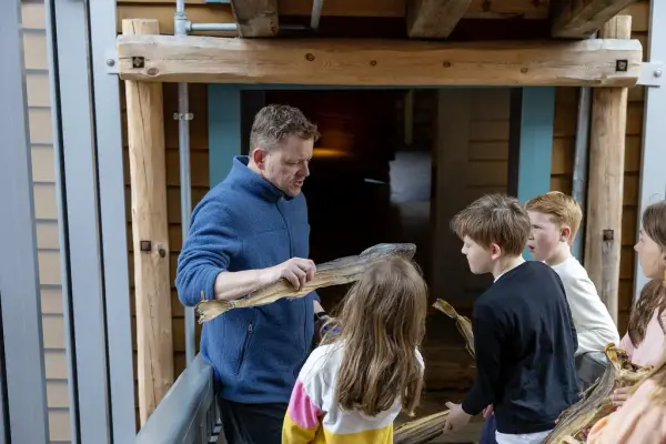 En av formidlerne ved museet forteller om sjøbodene for en gruppe med barn