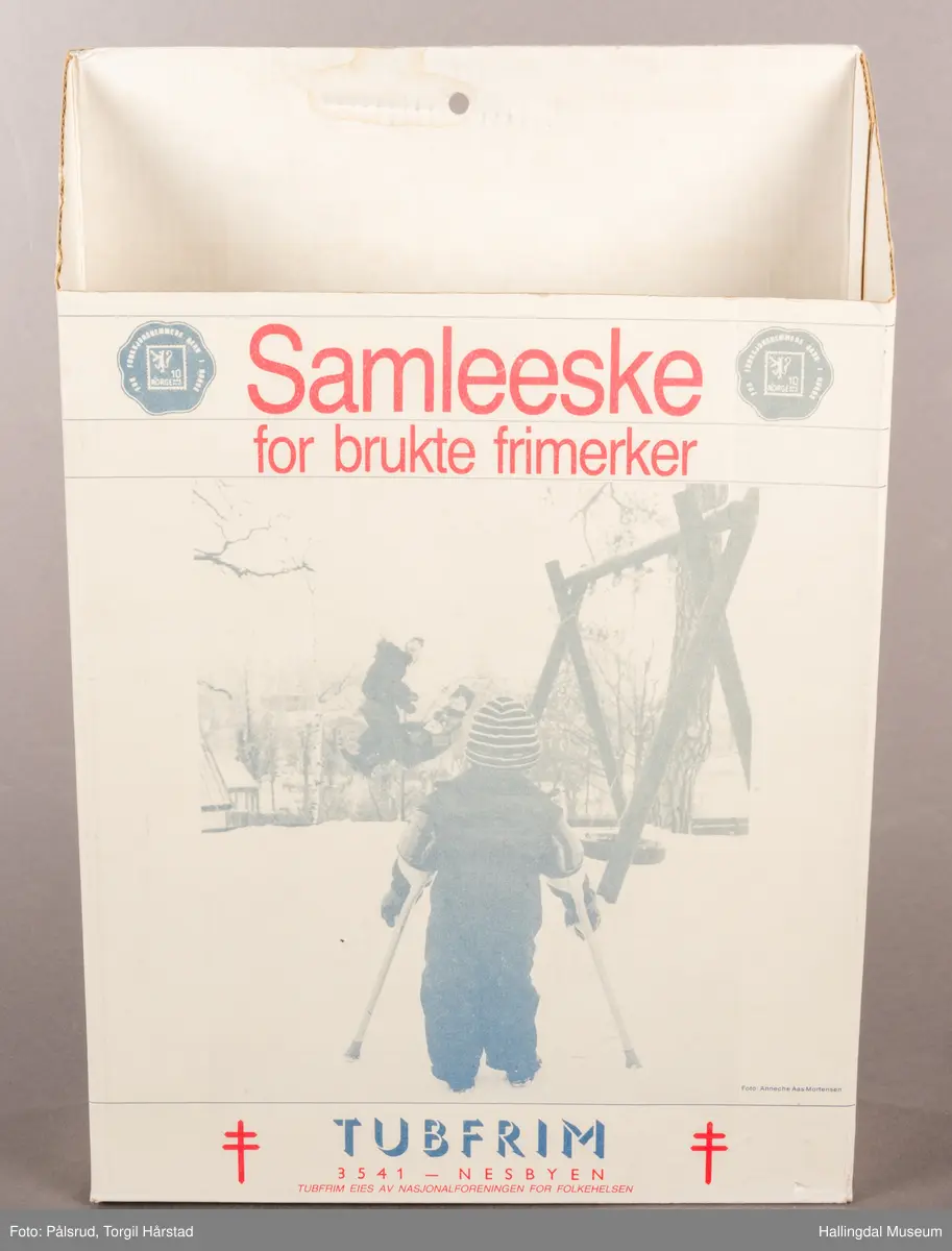 En hvit pappeskemed åpen topp. Bakplaten er høyere enn fronten, sidene skrår litt ned mot fronten. På fronten er det trykt på skrift: "Samleeske for brukte frimerker". Under et bilde at et barn med krykker forran et huskestativ står teksten: "TUBFRIM 3541 - Nesbyen. Tubfrim eies av Nasjonalforeningen for folkehelsen". I tillegg er det plassert små blå poststempler i de øverste hjørnene, en i hver. På hver side at den nederste teksten er det et rødt Lothringenkors, eller dobbeltkors. På den ene kostsiden står det en tekst i blå font med rød overskrift om hva Tubfrim er, stående over en illustrasjon av en rød saks som klipper bort et frimerke fra en konvolutt. Under står det "-Esken bes brukt om igjen ...". På den andre kortsiden står det en lengre tekst i blå font med rød oversikrift om hvordan eksen bør brukes, stående over den samme illustrasjonen med saks og konvolutt. Under dette står: "TUBFRIM N-3541 Norge. Tlf. 067-71094". 