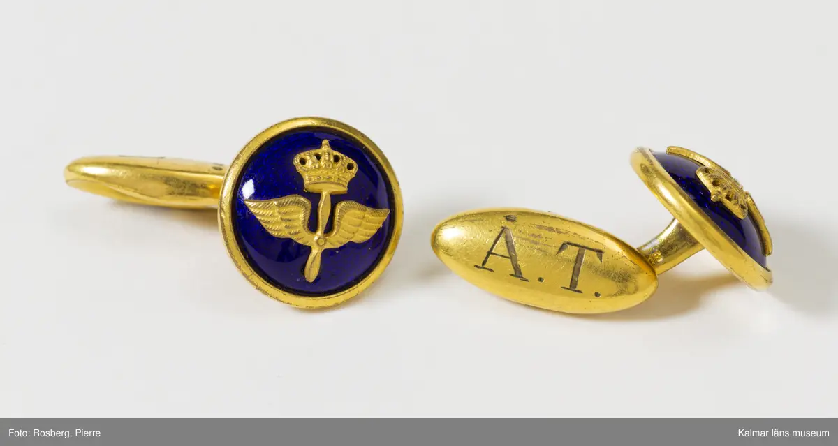 KLM 44534:24:1-2. Knapp, uniformstillbehör, 10 st. Åtta knappar och två manschettknappar. I ena fickan på Väst KLM 44534:4 hittades en ziplock-påse med åtta lösa små guldfärgade kulknappar med tre kronor och ett par manschettknappar med flygvapnets vapen på blå emalj, märkta med ÅT (Åke Torudd). Använda tillsammans med väst KLM 44534:4.