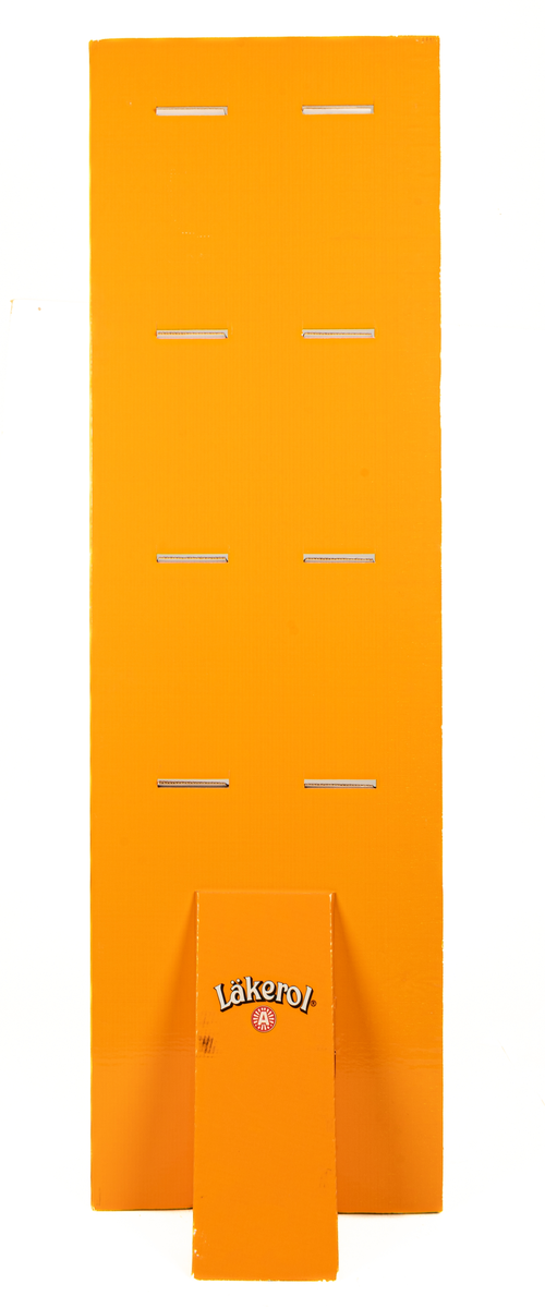 Reklamställ i papp, orange och vitt. Fyra fack för reklamartiklar. Tryckt text: Läkerol Make people talk.