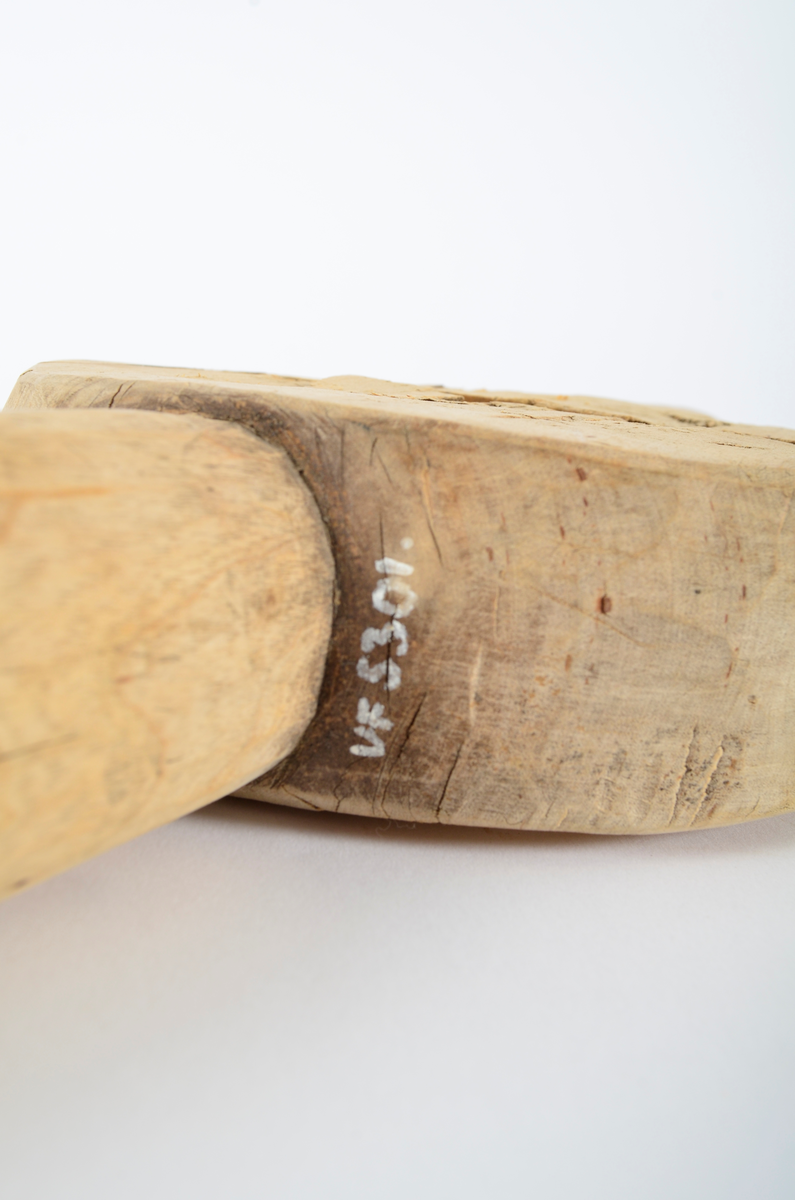 Består av sirkulær kloss med gjennombrutt smal fure i sentrum, ca. 12 cm lang. Horisontalt på furen, to runde håndtak. Smalner utover. Umalt.