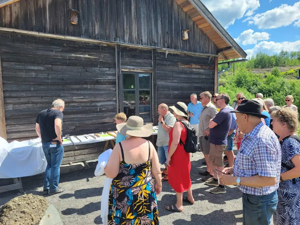 Presentasjon av smieredskap utenfor Iversmia. Museumsgjester står rundt og hører på foredraget.