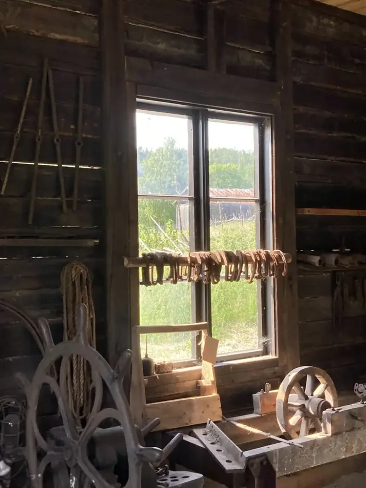 Interiør av Iversmia. Hestesko henger på rekke og rad på en stokk lagt tvers over vinduet.