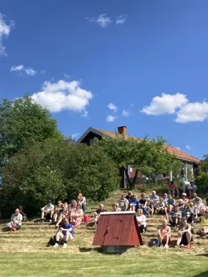 Museumsgjester sitter i skråningen på Almenninga under Grautdagen.