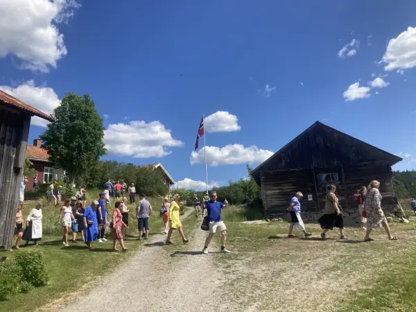 Museumsgjester krysser tunet på veg ned til Iversmia.