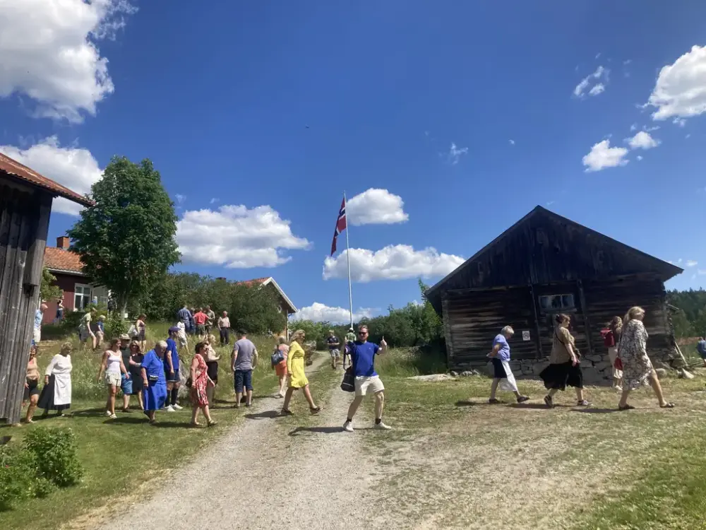 Museumsgjester krysser tunet på veg ned til Iversmia.