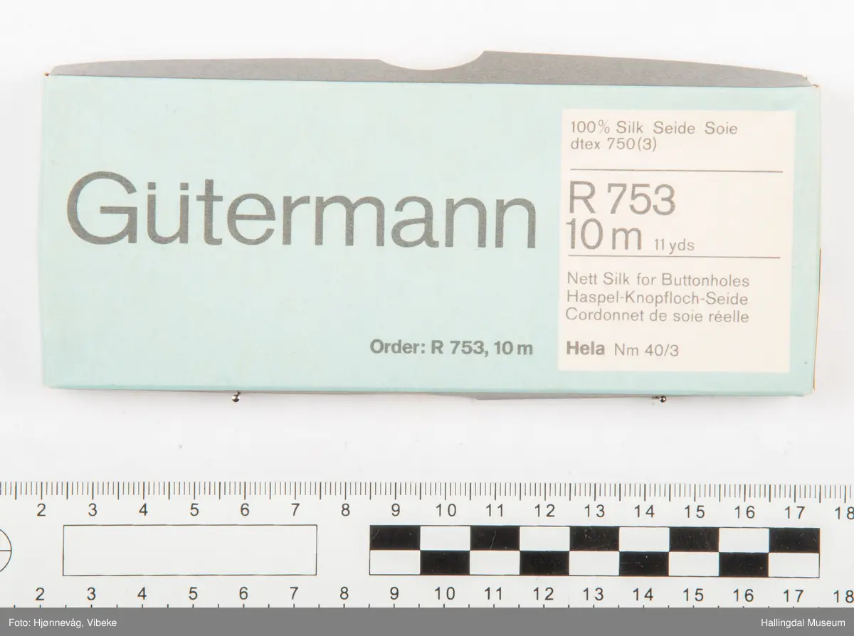 På lokket av esken er det trykt følgende:
Gütermann.
Inne i et firkantet felt står det følgende:
100 %Silk Seide Soie
d tex 750 (3)
R 753
10 m 11 yds
Nett Silk for Button holes
Haspel-Knopfloch-Seide
Cordonnetde sole rèelle
Order R 753, 10 m Hela Nm 40/3
På det ene endestykke står det skrevet "000 Gütermann R 753 10 m