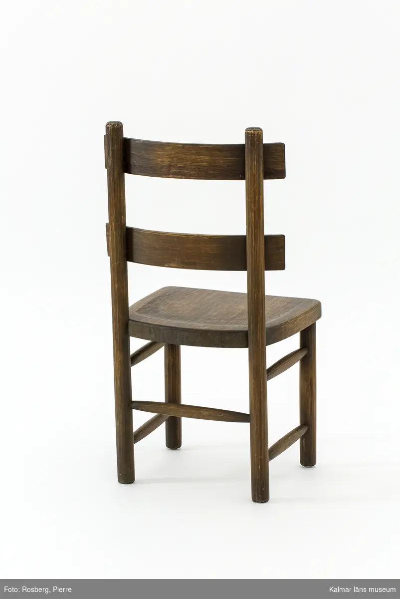 KLM 46378:2. Stol. Ingår i möbelserien "Sandhamn". Av furu med brunbetsad yta. Skålad sits. Ryggen består av två ribbor fastsatta med smidda järnspikar. Under stolssitsen en rektangulär metallbricka med text: AB NORDISKA KOMPANIET R 33845- MÖB.