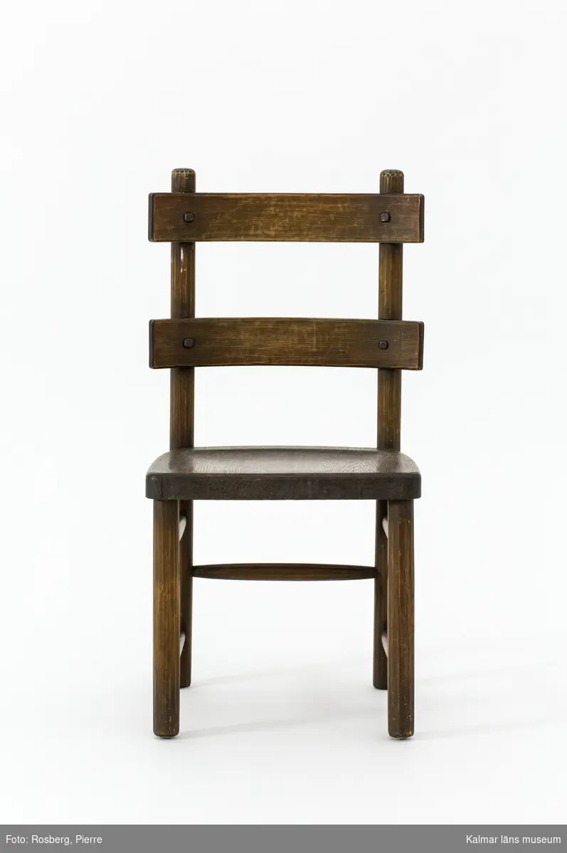 KLM 46378:2. Stol. Ingår i möbelserien "Sandhamn". Av furu med brunbetsad yta. Skålad sits. Ryggen består av två ribbor fastsatta med smidda järnspikar. Under stolssitsen en rektangulär metallbricka med text: AB NORDISKA KOMPANIET R 33845- MÖB.