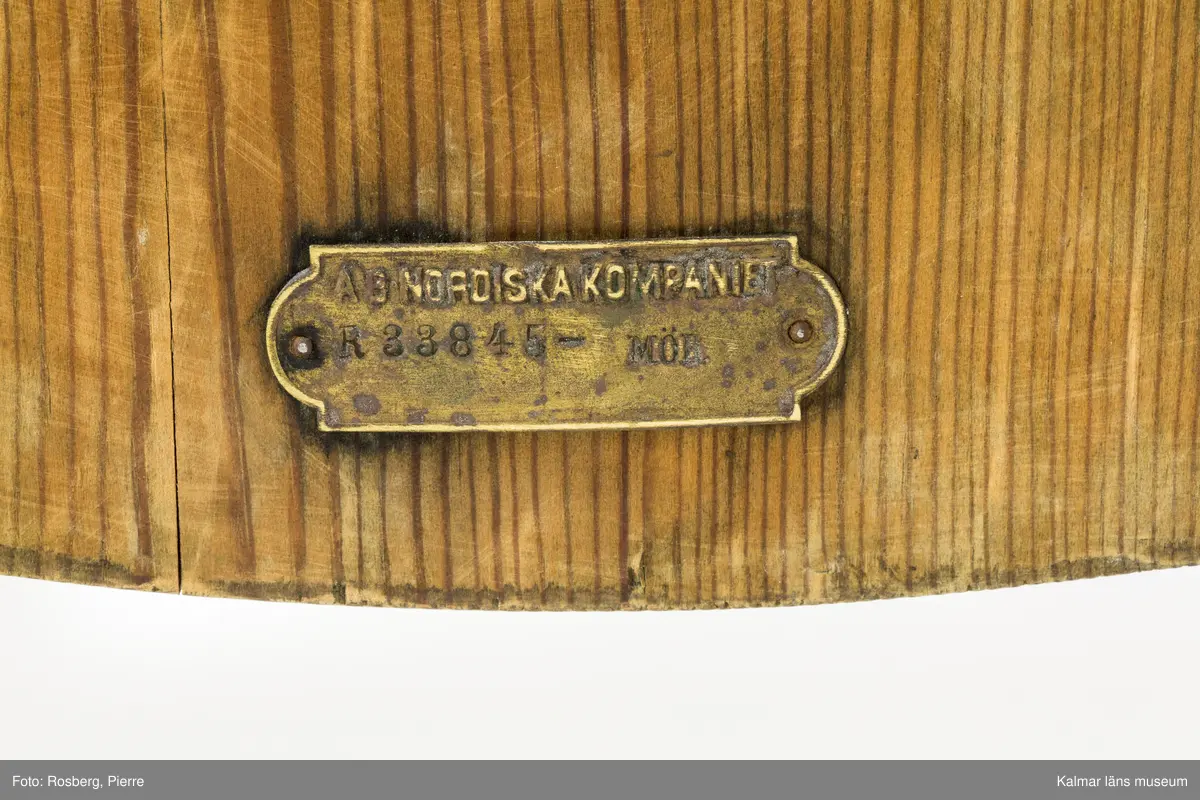 KLM 46378:3. Stol. Ingår i möbelserien "Sandhamn". Av furu med brunbetsad yta som senare även slipats. Skålad sits. Ryggen består av två ribbor fastsatta med smidda järnspikar, ena spikhuvudet saknas. Under stolssitsen en rektangulär metallbricka med text: AB NORDISKA KOMPANIET R 33845- MÖB.