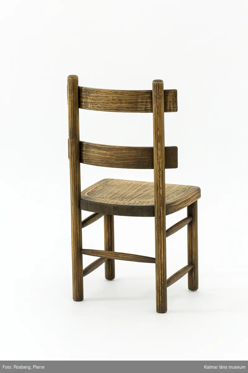 KLM 46378:4. Stol. Ingår i möbelserien "Sandhamn". Av furu med brunbetsad yta som senare även slipats. Skålad sits. Ryggen består av två ribbor fastsatta med smidda järnspikar. Under stolssitsen en rektangulär metallbricka med text: AB NORDISKA KOMPANIET R 33845- MÖB.