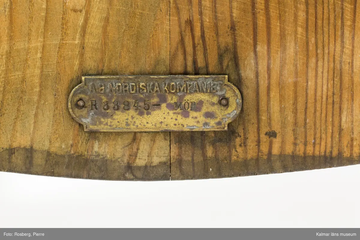 KLM 46378:4. Stol. Ingår i möbelserien "Sandhamn". Av furu med brunbetsad yta som senare även slipats. Skålad sits. Ryggen består av två ribbor fastsatta med smidda järnspikar. Under stolssitsen en rektangulär metallbricka med text: AB NORDISKA KOMPANIET R 33845- MÖB.