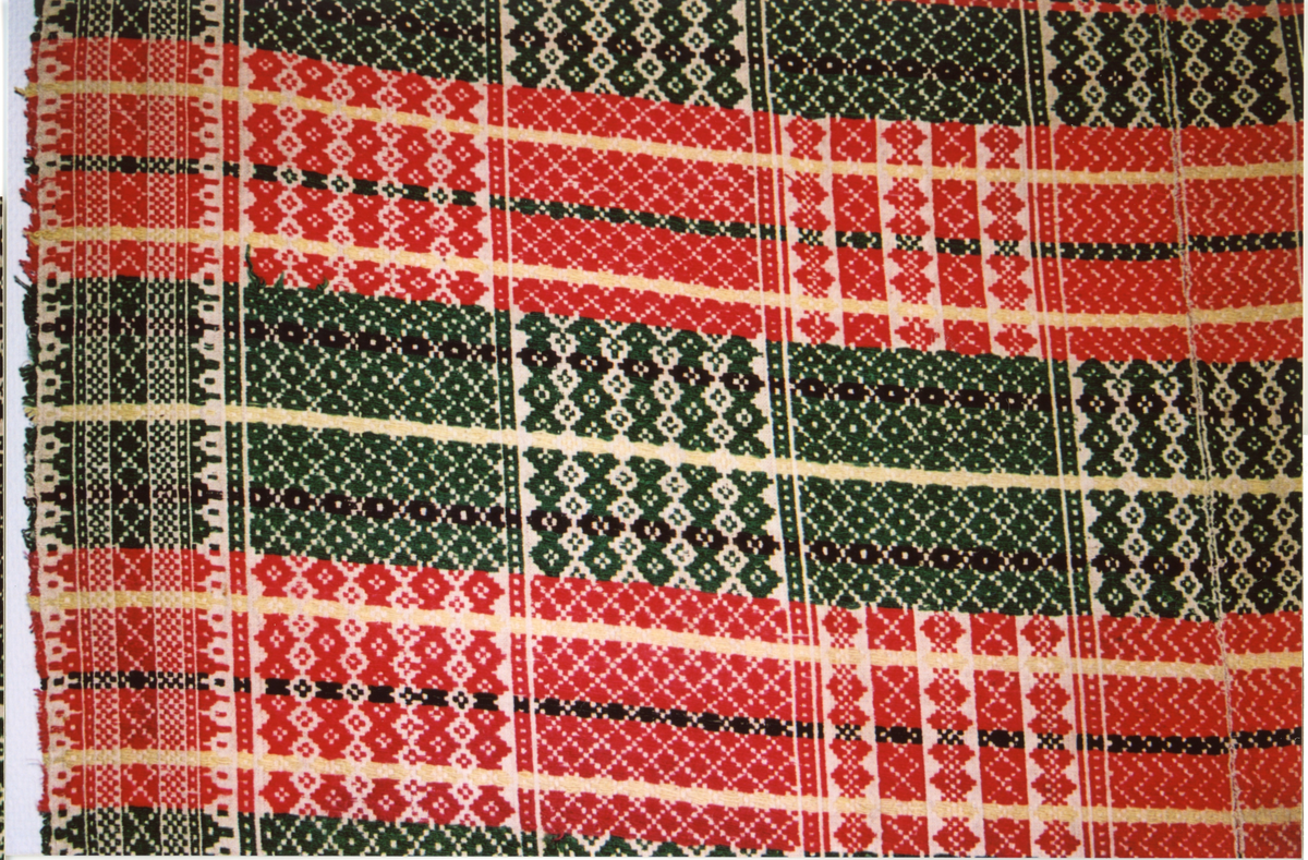 Fellåkle i skillbragd. Eies av Røros Museum.

Tilstanden er god, noe slitt og falmet.

Farger: 
Renning lin: Ubleket.
Innslag lin (ull?): Grønn 679, Rød 639 men gulere, Gulgrønn 650 men lysere, Mørk brun 610 men grønnere, Brun 620 men lysere.