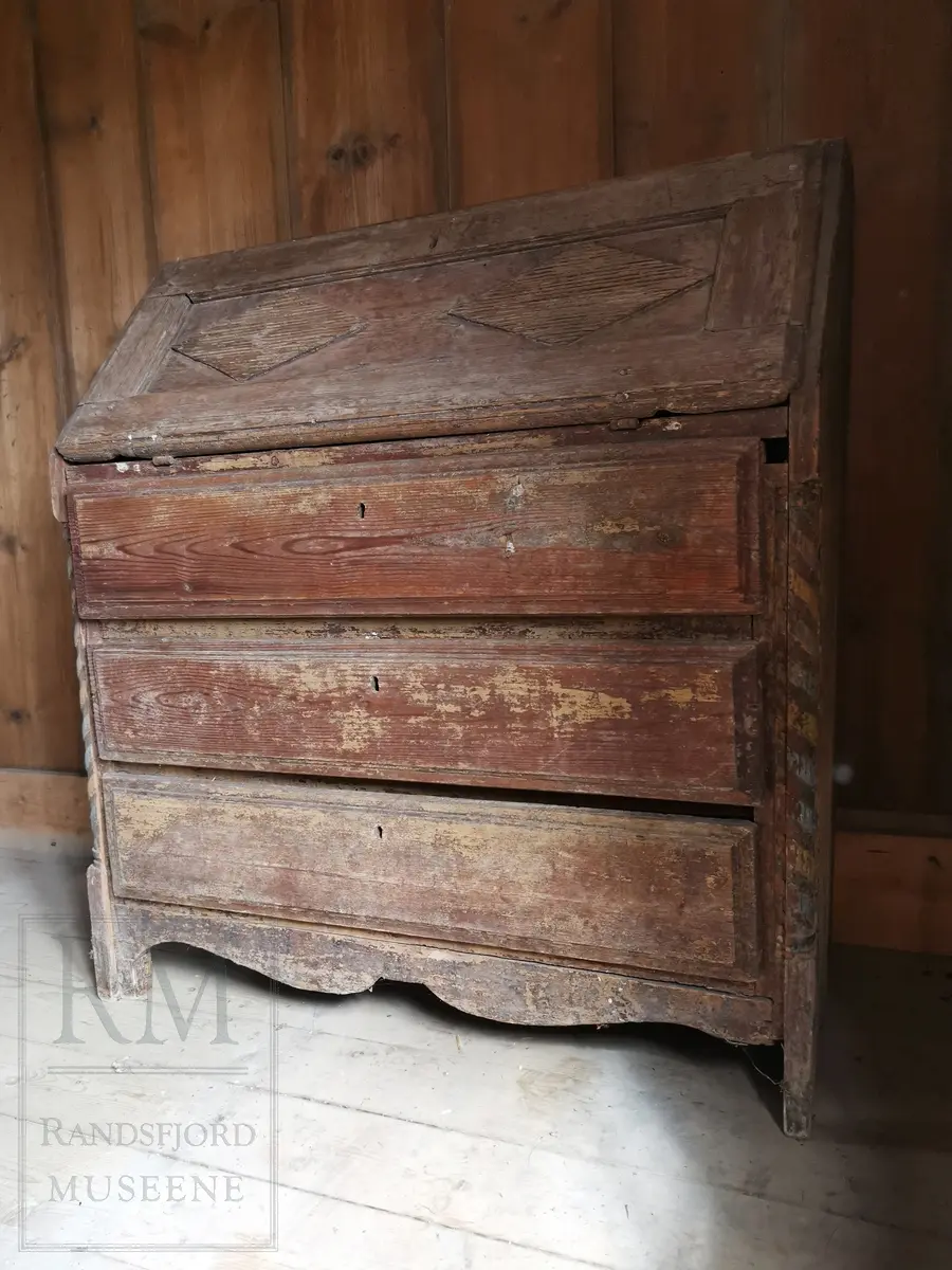 Med tre skuffer og nefellbar klaff. I klaffen er det rilledekor i to ruter-felt