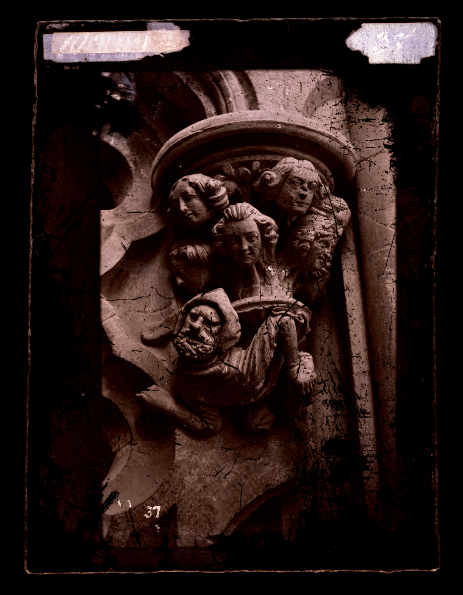 "Byggmesteren og hans svende" - konsoll fra oktogonskranken i Nidarosdomen. Kapitel med sju hoder. Skulpturen er plassert ved nordre inngang til ambulatoriet, vendt mot ambulatoriet.
I følge Hovedkatalog for fotografier er bildet tatt etter restaurering.