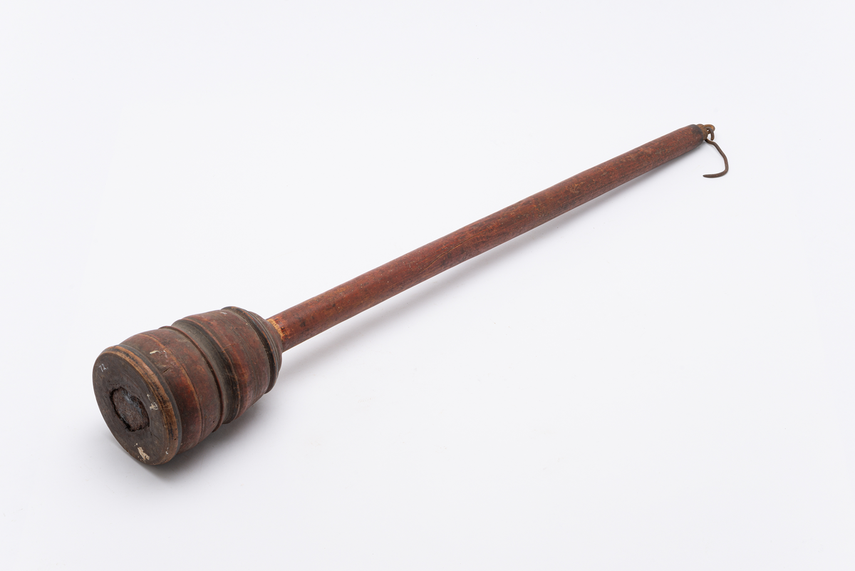 Rødmalt bismervekt i tre med vektkrok. Profilert dreid vektkule med enkelstrekdekor. Målemerker i metall.