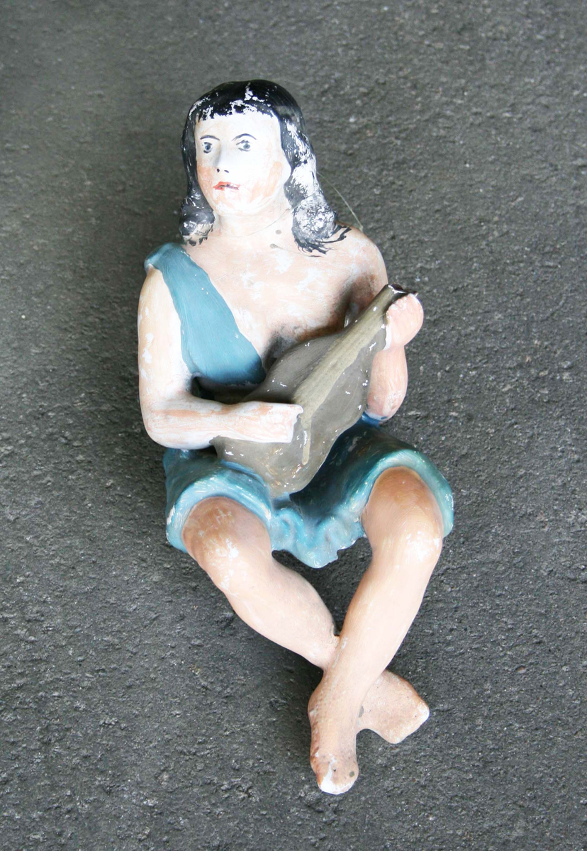 Kakelugn i vitt, med inslag av guld och polykrom dekor. Hög och fyrsidig. Bestående av sammanfogade, rektangulära plattor. Framsidan med oval nisch, i form av polykrom och förgylld medaljong, med dekor av "sittande flicka med hund i famnen framför musselskal". Ramen delvis förgylld samt med fyra rosor. Kakelugnens krön, med lutspelande sittande figur, flankerad av böljande blad- och volutformade ändar. Nedanför krönet, rosett- och bladornamentik inom förgyllda lister, samt ventilationslucka av mässingsplåt. Längst ned luckor i järnplåt. Delarna förvaras i trälådor.

Äldre historik: 
Kakelugnen härstammar troligen från en gammal byggnad, som förstördes i sista branden 1877 i Borås.

Funktion: För uppvärmning av bostadshus