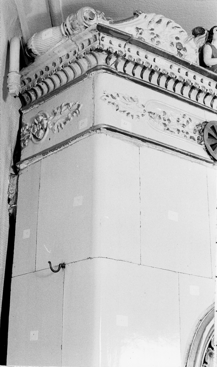 Kakelugn i vitt, med inslag av guld och polykrom dekor. Hög och fyrsidig. Bestående av sammanfogade, rektangulära plattor. Framsidan med oval nisch, i form av polykrom och förgylld medaljong, med dekor av "sittande flicka med hund i famnen framför musselskal". Ramen delvis förgylld samt med fyra rosor. Kakelugnens krön, med lutspelande sittande figur, flankerad av böljande blad- och volutformade ändar. Nedanför krönet, rosett- och bladornamentik inom förgyllda lister, samt ventilationslucka av mässingsplåt. Längst ned luckor i järnplåt. Delarna förvaras i trälådor.

Äldre historik: 
Kakelugnen härstammar troligen från en gammal byggnad, som förstördes i sista branden 1877 i Borås.

Funktion: För uppvärmning av bostadshus