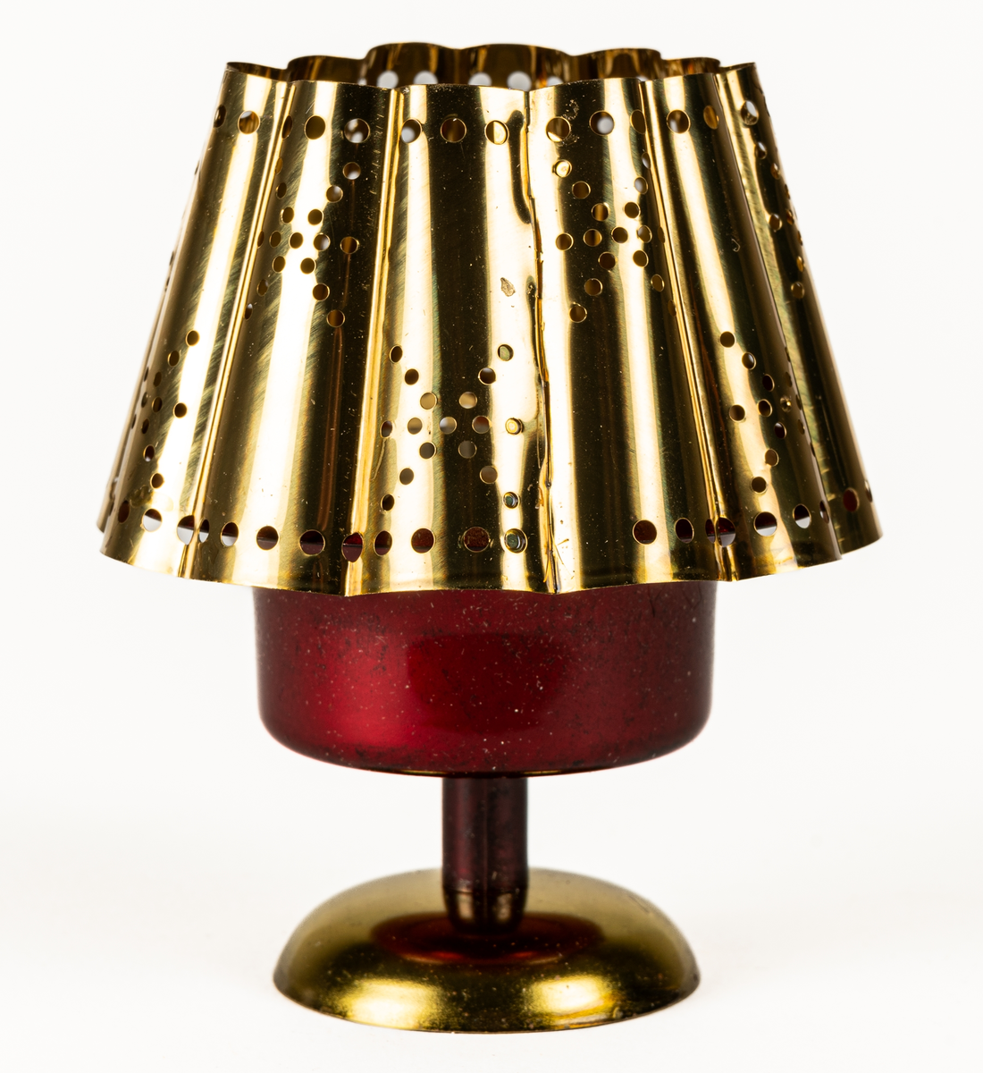 Ljuslykta för levande ljus, s.k. kuvertlykta. Röd fot med plats för ljus, vågig skärm, perforerad. Tillhörande blå originalask i papp.