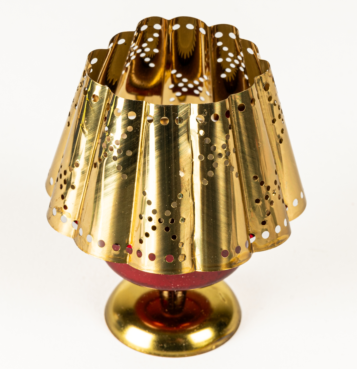 Ljuslykta för levande ljus, s.k. kuvertlykta. Röd fot med plats för ljus, vågig skärm, perforerad. Tillhörande blå originalask i papp.