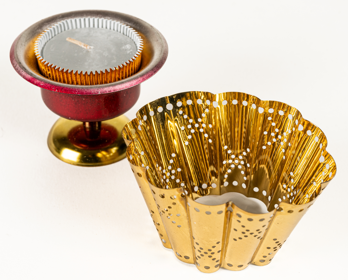 Ljuslykta för levande ljus, s.k. kuvertlykta. Röd fot med plats för ljus, vågig skärm, perforerad. Tillhörande blå originalask i papp.