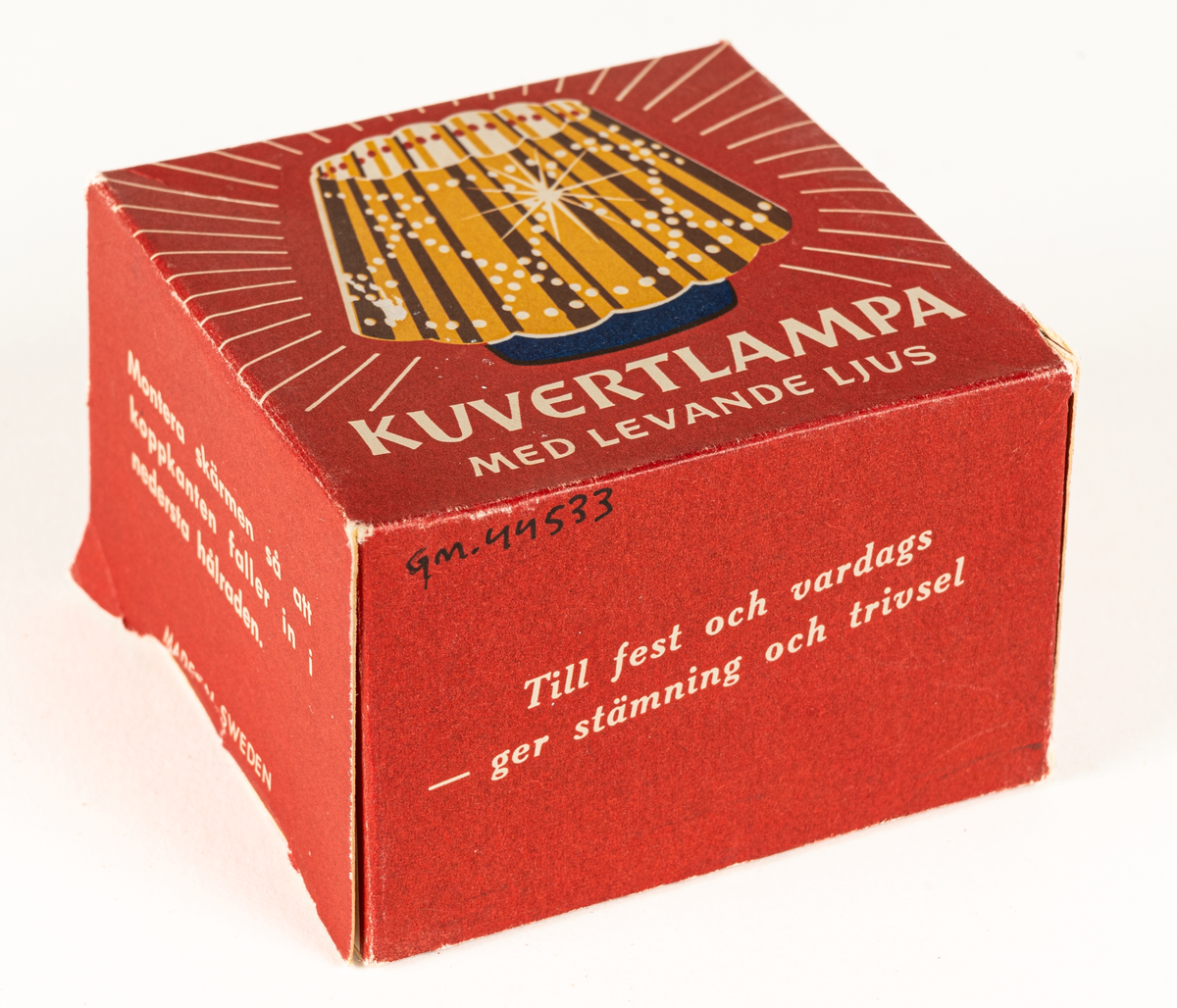 Ljuslykta för levande ljus, s.k. kuvertlykta. Blå fot med plats för ljus, vågig skärm, perforerad. Tillhörande röd ask i papp.
