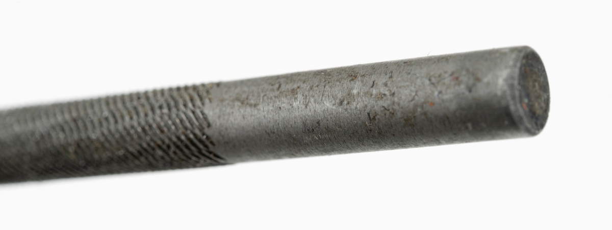 Fil, rundfil, konstruert for kvessing av skovltannkjeder på motorsager. Dette er ei rundfil med 4,8 millimeters diameter. Den «frie» delen av rundfila er 16,2 centimeter lang, men enden  av denne stålkomponenten er ført inn i et skaft av oransje plast. Stålfilas lengde er totalt 24,5 centimeter. Filskaftet er påført tallene 30 og 25 som er filingsvinkler brukeren kunne rette seg etter ved skarpfiling av sagkjedene. (Annen påført tekst på fil og skaft er innført under fanen "Påført tekst/merker".)

Fila framstår som tilnærmet ubrukt. Det antas at fil og skaft har vært med i et medfølgende verktøysett til en ny Husqvarna motorsag.

[For mer informasjon om filing av sagkjeder, se skannet litteratur vedlagt under fanen "Referanser til filer".]