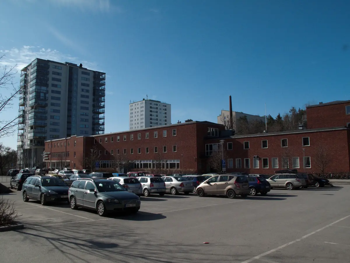 Näsbyparkskolan från norr med huvudbyggnad och framförvarande parkering.