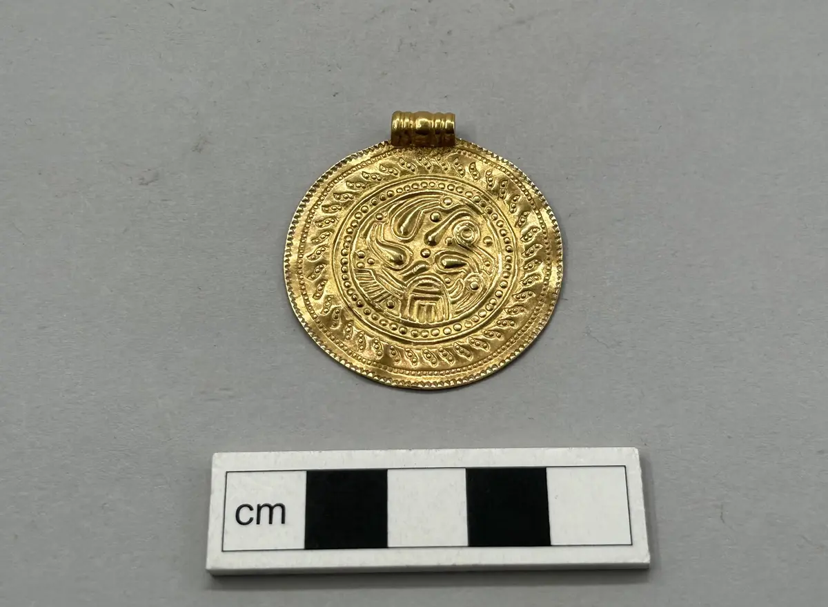 Gotländsk e-brakteat av guld med stämpeldekor och triskelmotiv i centrum.enbart Präglad på ena sidan kompl mars 2006/ml
av guld med ögla. Funnet vid jordbruksarbete vid s:t västergårda i fide, av lantbr. Helge jakobsson, s:t västergårda. Inköpt för  60 kronor och skänkt till gotl. Fornsal av fru ada block, visby.  Med riksantikvariens medgivande tillförd gotl. Fornsals samlingar, konc.nr. 71/36, 80/36, 97/36, 110/36, dnr. 82/36