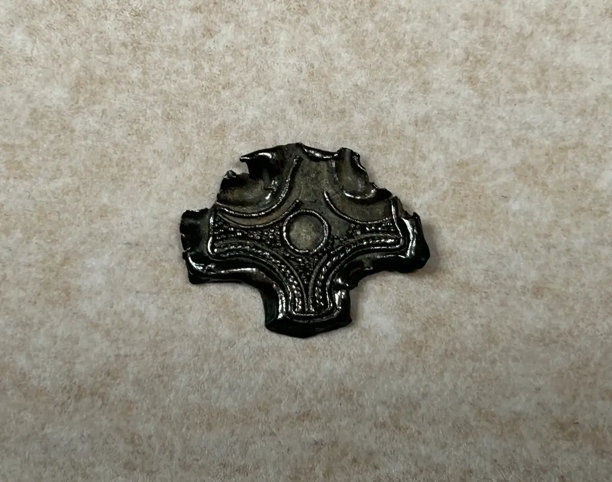 AV SILVER, KORSFORMIGT, SAMMA TEKNIK SOM FÖREGÅENDE, (8914:1). ÄVEN GRANULATION ANVÄND. 1,6 x 1,9 CM. FRÅN HEMÄNGE I ETELHEM.  PÅTRÄFFAT I "VÄLDESÅKERN" AV LANTBR. EDV. PETTERSSON, HEMÄNGE ETELHEM, EFTER UNDERS. AV DOC. M. STENBERGER.