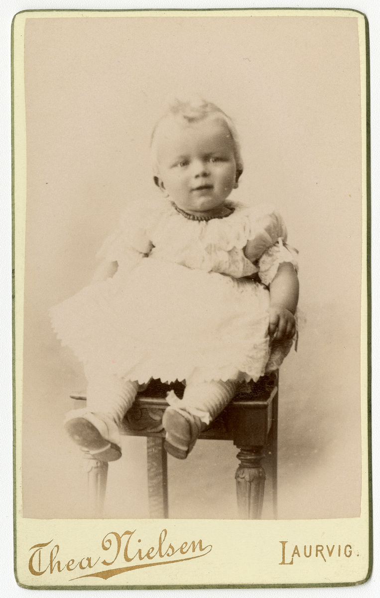 Portrettfoto av ukjent spedbarn som sitter på barnestol