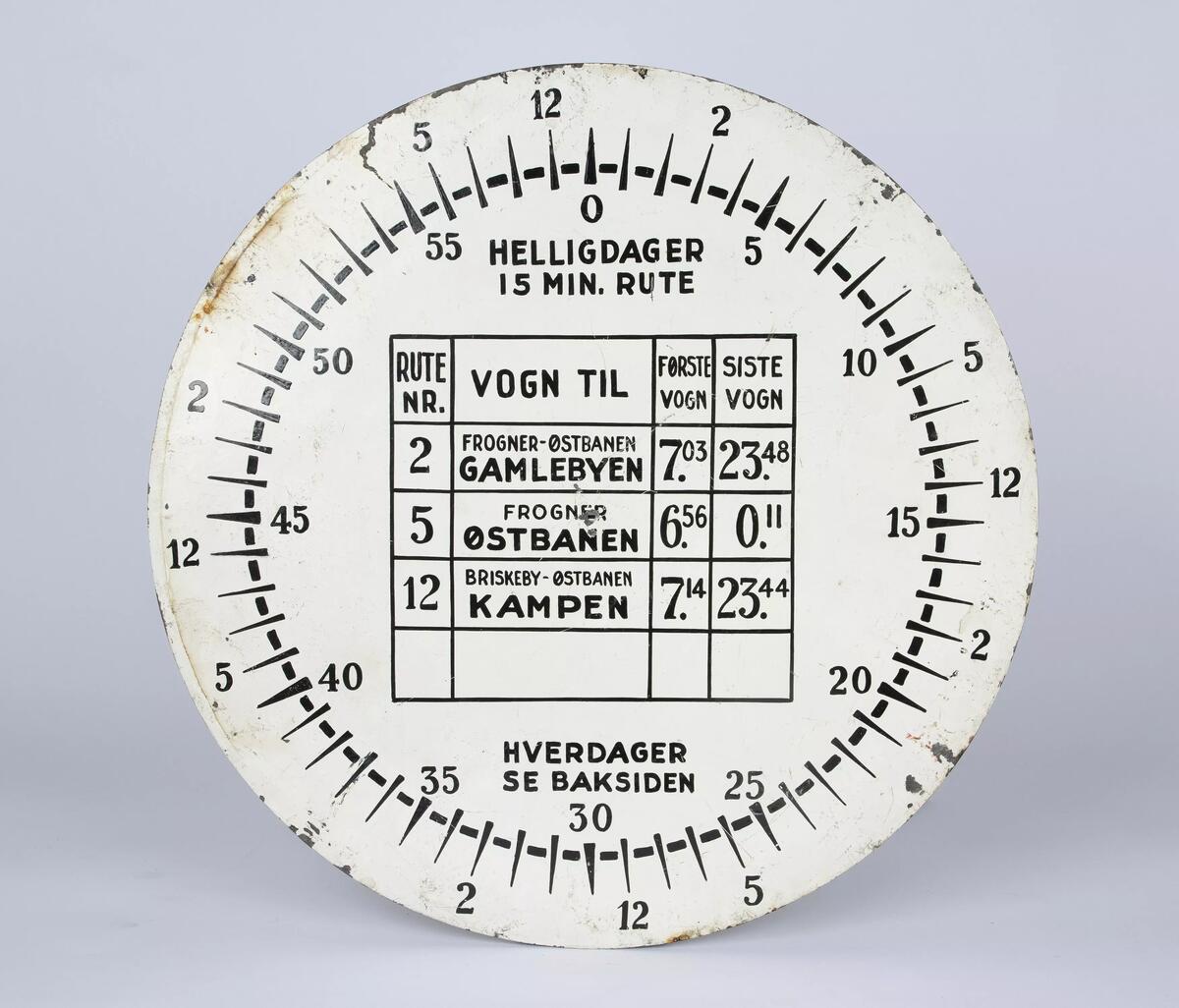 Rundt skilt kalt "klokkering" for rute nr. 2, 5 og 12. Mange slike skilt ble laget og plassert rundt i Oslo på 1950- og 60-tallet. Skiltets bakside er helhvit, og med tanke på teksten "hverdager se bakside" på skiltets forside så er baksiden trolig malt over. 