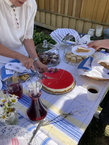 Nærbilde av kaker og saft på serveringsbok. Blomster på bordet.