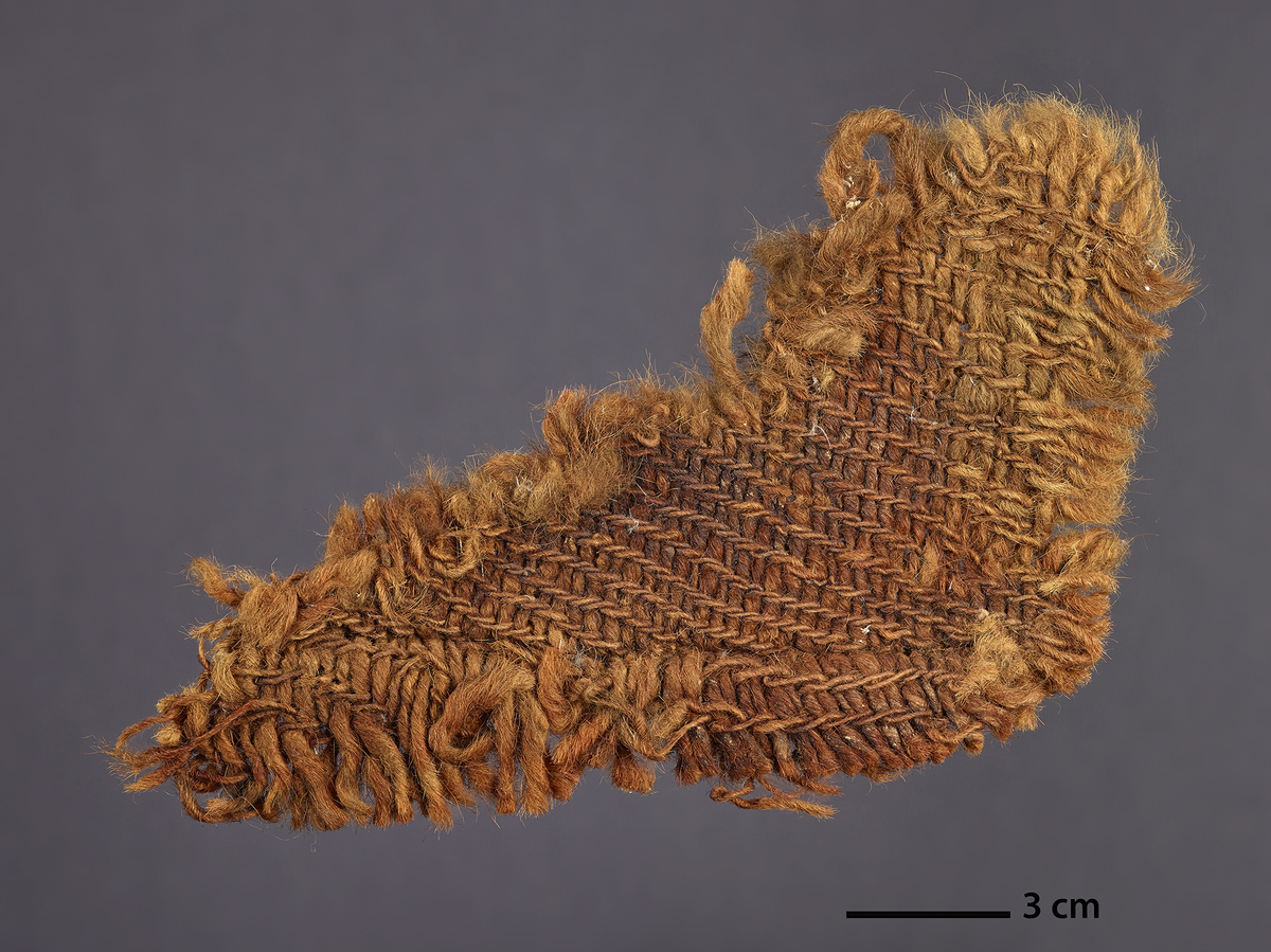 Tekstil fragment (Tidligere nummer T.03), samt tre prøver (tidligere nummer T03a, T03b og T03c).
Ifølge rapport fra 20.11.90 ble disse funnet på samme lokalisering som undernummer 1. Beskrives som to duker/staver (i seglet) som er sydd sammen. Man ser en annen sømteknikk enn i prøve nr. 2. Analysen skrevet på svensk oppgir følgende: Varp: ca. 6,5-7 tr/cm (13 tr på 2 cm), Z-spunnet,hardt - middels hards spunnet, tråd ca. 1 mm i diam. Innslag: ca. 3,5 tr/cm (7 innslag på 2 cm), S-spunnet, ikke spunnet - løst spunnet, tråd ca. 2 mm i diam. Vevteknisk likesidet 2/2 kypert,  men utseendemessig ulike på hver side. Den ene siden som ifølge søm er rettsidet har mer fremtredende varp og høyrekypert - høyrediagonal. Dateres til 1280-1400 evt.

Analysen skrevet på dansk: 34 1/2 x 10 cm stort tekstilfragment, godt innsmurt i tjære/smøring. Ingen synlige kanter, men i den ene enden ses noe som kan være en sammensying, hvorav en tykk ullsnor stikker opp. Teknikk 2/1 kypert, spinning Z/S, trådantall 6/4 tr/cm. Fibrene er ull, rødbrun farge, Varpen meget pigmentert her, innslaget også med pigmenterte hår med farge. Ingen bevegelighet i stoffet pga smøring. Snor teknikk: S-spunnet tråd