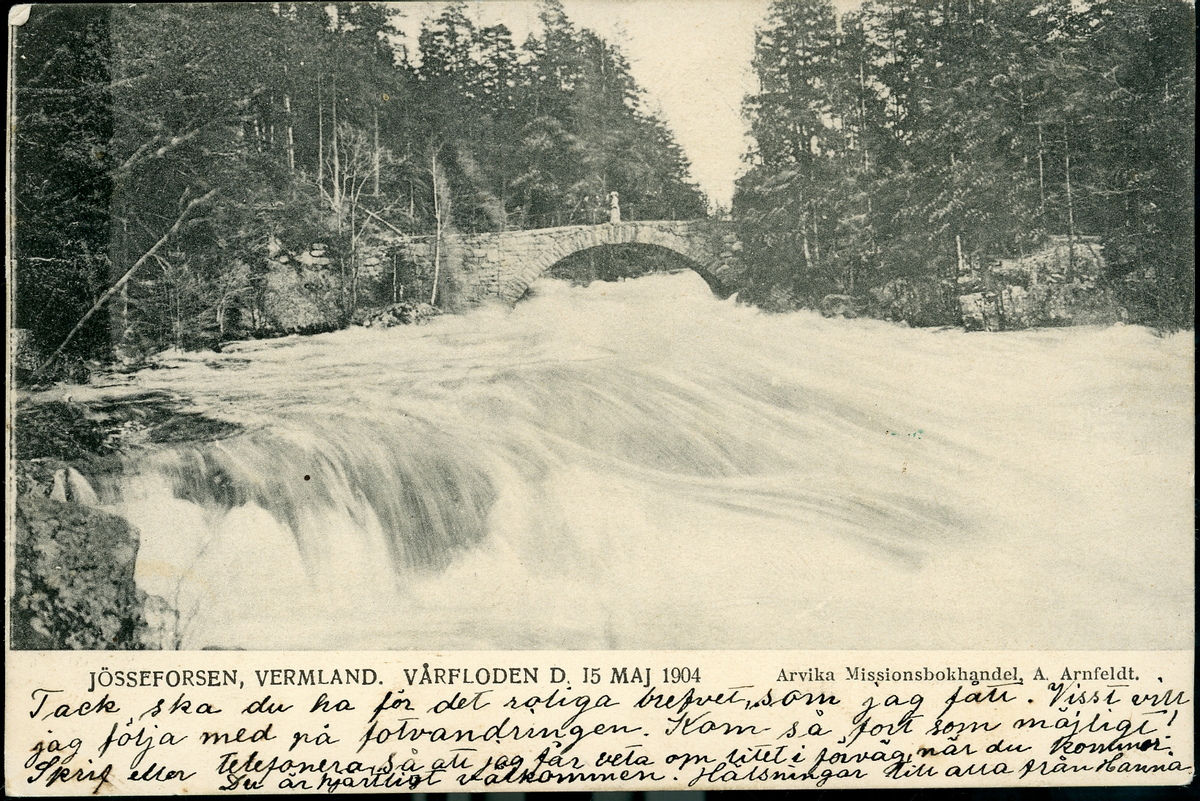 Reproducerat svartvit fotografi förställande Vårfloden den 15 maj 1904, Jösseforsen
Påskrift: Jösseforsen, Vermland. Vårfloden d 15 maj 1904 - Arvika Missionsbokhandel, A. Arnfeldt.