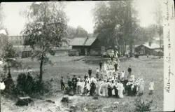 Svartvit bil av en grupp människor i landskap. 
Påskriven te