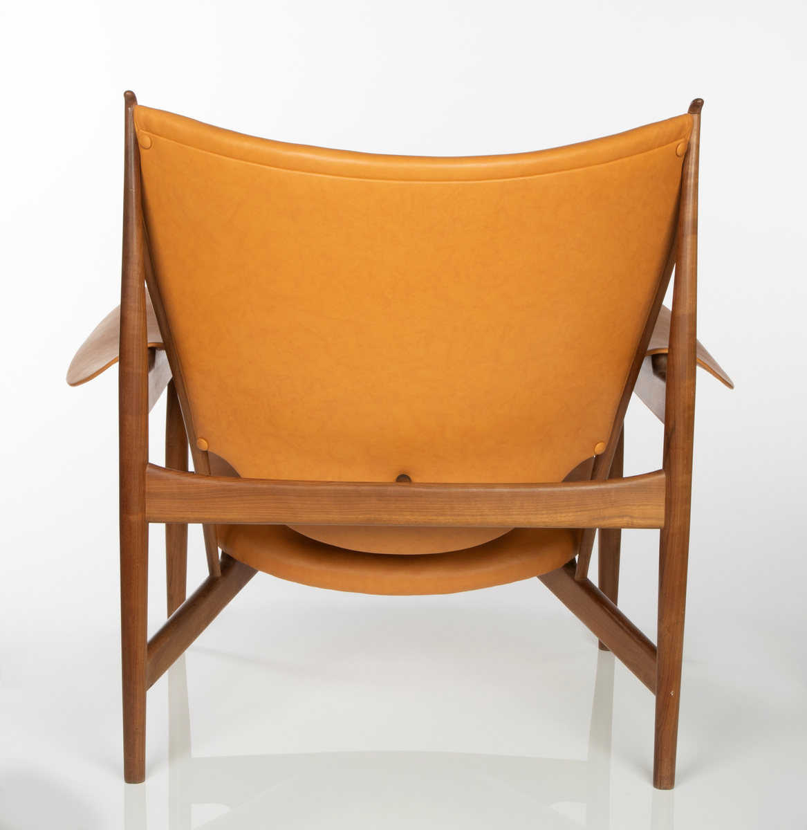 Stol, utført i brasiliansk valnøtt (imbuia). Åpen konstruksjon med fire runde ben, med størst tykkelse på midten, helt vertikalstilt. For- og bakben er forbundet med kraftig tverrligger som danner støtte for armlenene av buede stålplater. Mellom forbenene en bred sargsprosse som tiltar i høyde mot midtpartiet hvortil setets forkant er festet. Denne sprosse opptar i seg to kraftige, skråstilte og horisontale setestøtter fra bakbenene, og disse gir igjen feste for to spinkle, runde ryggstøtter som øverst møter bakbenene i en spiss vinkel, avsluttet med en liten knottforlengelse. Kraftige støttesprosser mellom bakbenene i rygghøyde samt kort tverrstøtte mot ryggplaten. Sete, rygg og armlener er fint og komfortabelt buet og trukket med lys oksehud. Stopning i sete og rygg. Både sete og armlener har få konsentrerte festepunkter til trekonstruksjonen og er skjult på undersiden. Dette gir sete og armlener en lett svevende virkning, som også understrekes av at setebredden er mindre enn trekonstruksjonens sitteåpning. Stolen har treets naturlige brune farge, med glattpusset overflate og avrundede kanter og hjørner.