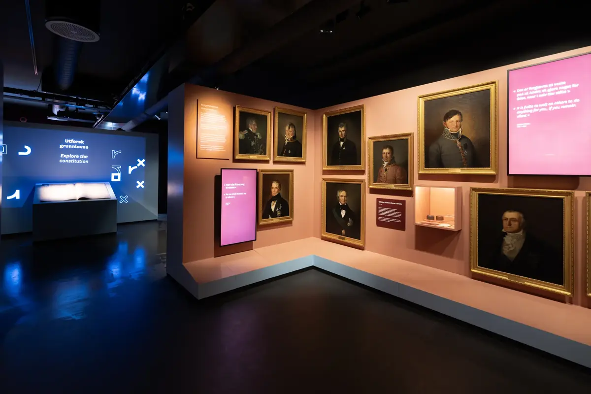 Portretter av Eidsvollsmenn og digitale skjermer i utstillingen på demokratisenteret Wergelands Hus.