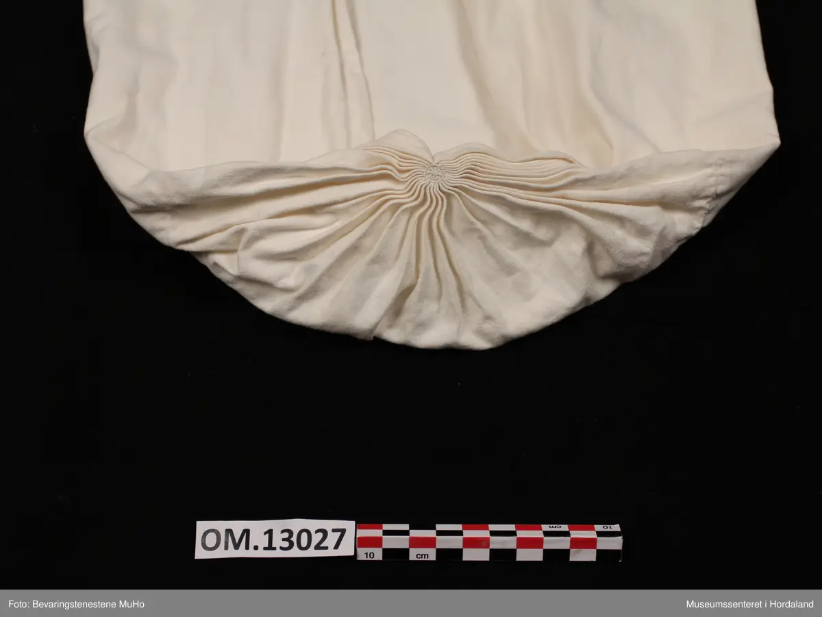 Kvithua er i bomull og har dobbelt stoff i største delen av hua, den delen av hua som skal festast rundt hovudet. Dette stoffstykket er avlangt og firkanta. I den andre enden (den som skal hanga ned på ryggen) er det enkelt stoff. Dette stykket er rynka saman som avslutning. Oppå samanrynkinga er det brodert eit lite rundt broderi med kvit tråd. Hua er open midt under.