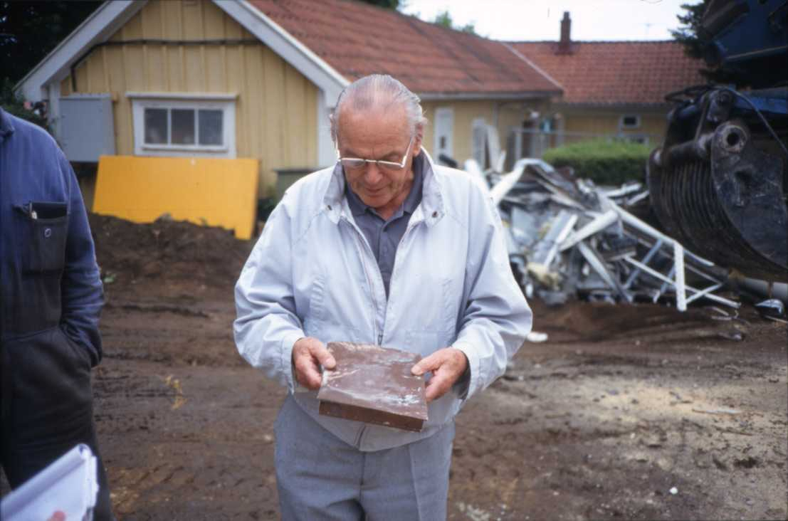 Före detta museichef Olof Fong står på en byggarbetsplats med en kopparbox - en tidskapsel - i händerna.