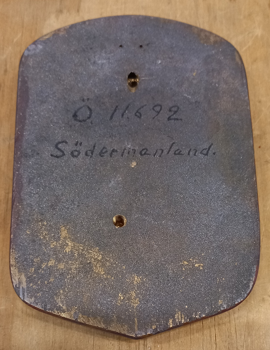"I fält av guld an upprest svart grip med röd beväring, därest sådan skall komma till användning"