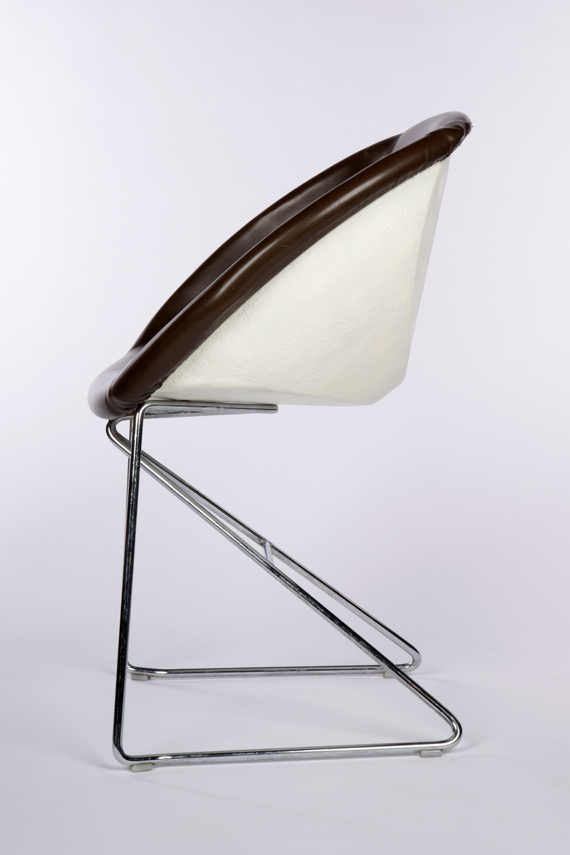 Tilnærmet halvkuleformet stol med hvit skall av plast (glassfiberarmert polyester) på et lett forkrommet stålrørunderstell. Mørkebrunt avtagbart trekk av skai (skinnimitasjon). Stabelbar.