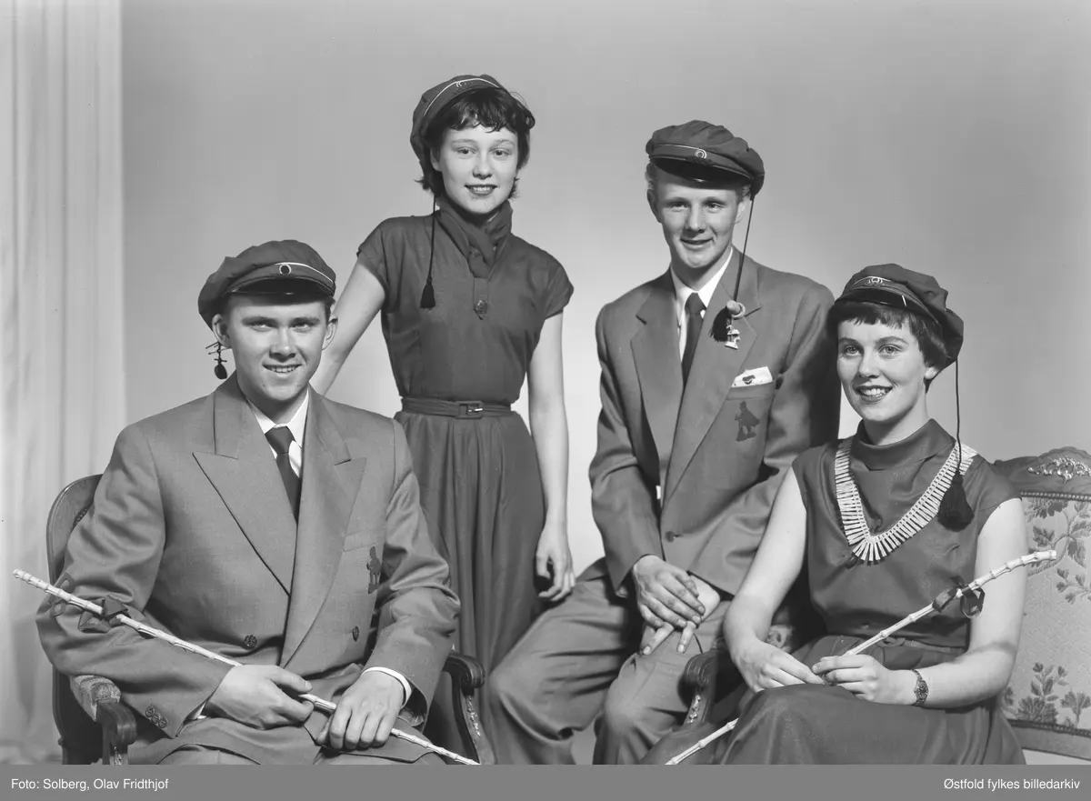 Gruppeportrett av russ 1955, personene er ukjente. Antakelig gymnasiaster fra Sarpsborg. Med russelue og russeknute og russestokk av bambus. Atelierfoto.