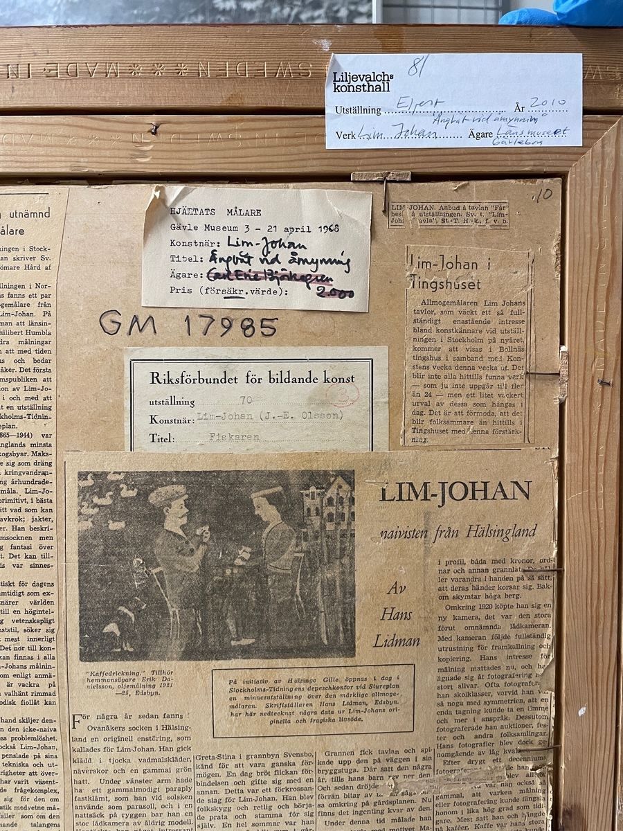 Oljemålning på kartong av Lim-Johan (Johan Erik Olsson) "Ångbåt vid åmynning", 1914-1923. 
Två män metar vid en bro över en åmynning. I bakgrunden en ångbåt, över vilken en stor klöverblomma reser sig som ett träd. På baksidan en mängd gamla tidningsklipp.