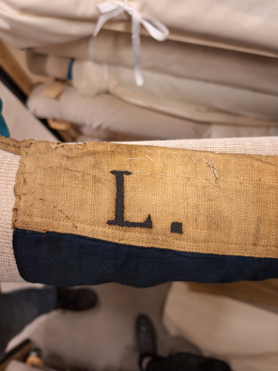 Flagga av bomull, fyra fält, det övre inre fältet blått, det undre gult, det yttre fälten vice versa. Splitsad strop med spolformad låsknapp av trä. Bokstaven L, märkt med svart färg på övre delen av stående liket. (L enligt Commercial code fr 1857)

Enligt C. E. Stenius, Handbok för sjöfarande, Åbo 1874, se sid 380:
Viktiga afstånds-signaler.
"För att på ett hastigt sätt äfven kunna signalera meddelanden av särdeles vigt, har man gifvit dessa aderton signaltecken utom deras alfabetiska också en annan betydelse, nemligen: återgifvande af hela meningar och för att tillkännagifva, att de hissade signalerna just hafva denna betydelse, hissas kulan ensamt efter hvarje signal. Till de mest vigtiga afstånds-signalerna räknas dock de fyra sammansättningarna med två tecken."...
L. betecknar: Behöfver lots. Kan jag få någon?